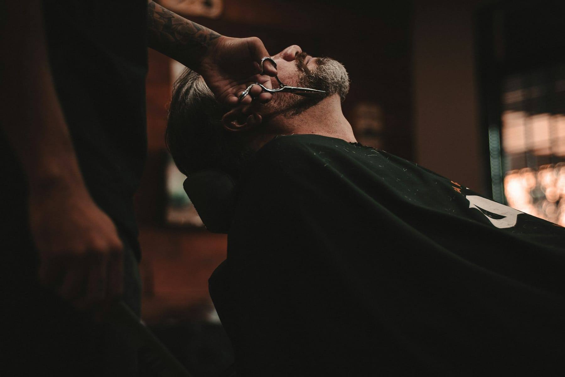 Barber shaving a client in low light